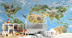 A bright nursery room wall featuring an illustrated world map wallpaper with animals, paired with a white wooden crib.