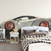 The automotive mural in a bedroom or den, styled with dark industrial metal accents.
