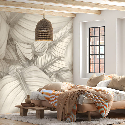 A serene bedroom with a large-scale botanical leaf mural behind a wooden headboard.
