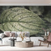 A serene living room featuring a large, dewy leaf mural on the wall behind a minimalist wooden bed frame.