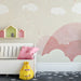 A cozy playroom for kids with a dreamy cloud and star pattern mural wallpaper.