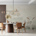 A light-filled farmhouse dining room featuring a subtle watercolor landscape wall mural behind a sofa.