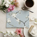 Dining room interior with elegant blue botanical wallpaper and minimal modern furniture.
