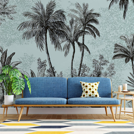 Blue sofa with a decorative pillow in front of a tropical wall mural with palm trees.