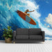 Black sofa in front of a wall mural of a surfer on an orange surfboard with blue ocean waves.
