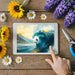 Tablet displaying a scenic image of a surfer on a wave, surrounded by sunflowers, daisies, and lavender on a wooden surface.